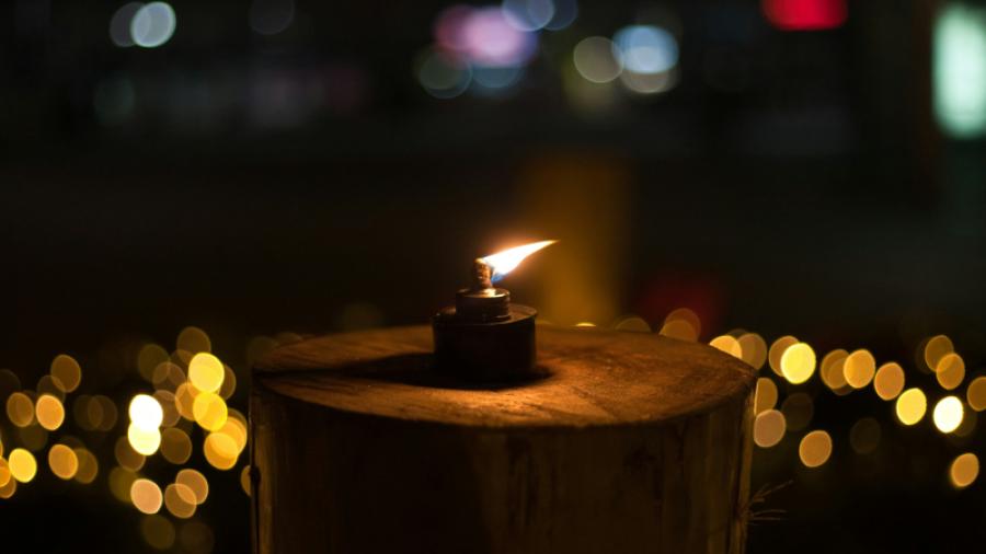 Foto av Marina Dina vid Unsplash.com som föreställer en tänd lykta på en stubbe omgiven av ljus.