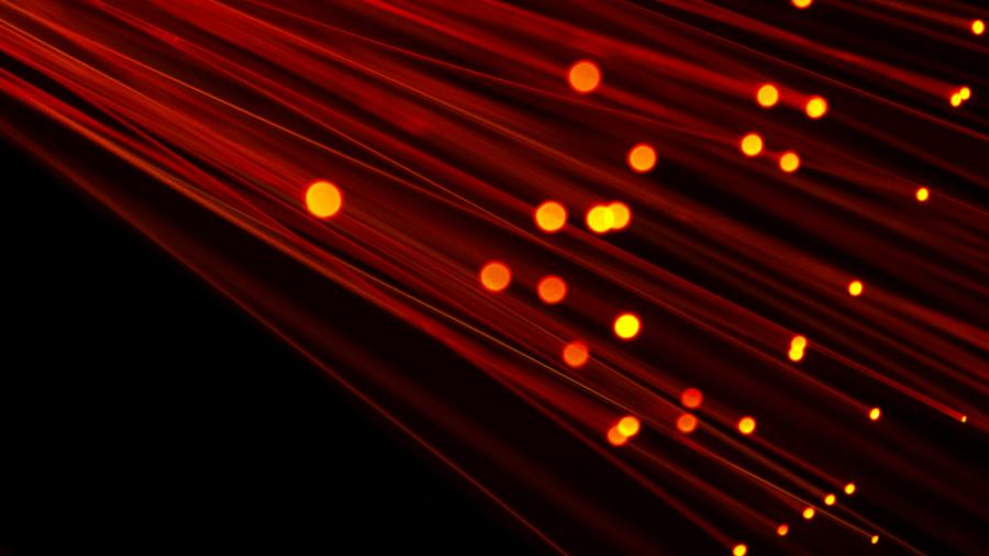 Foto som föreställer separerade trådar av optisk fiber som lyser upp med orange och gul varm färg.