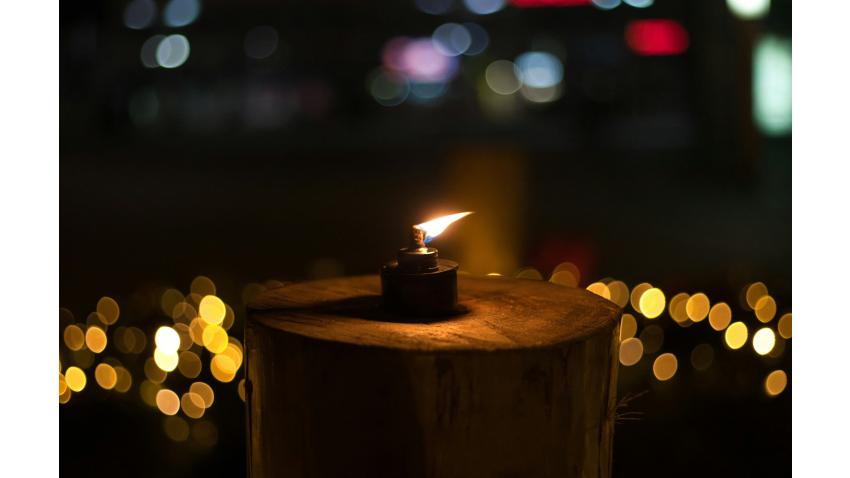 Foto av Marina Dina vid Unsplash.com som föreställer en tänd lykta på en stubbe omgiven av ljus.